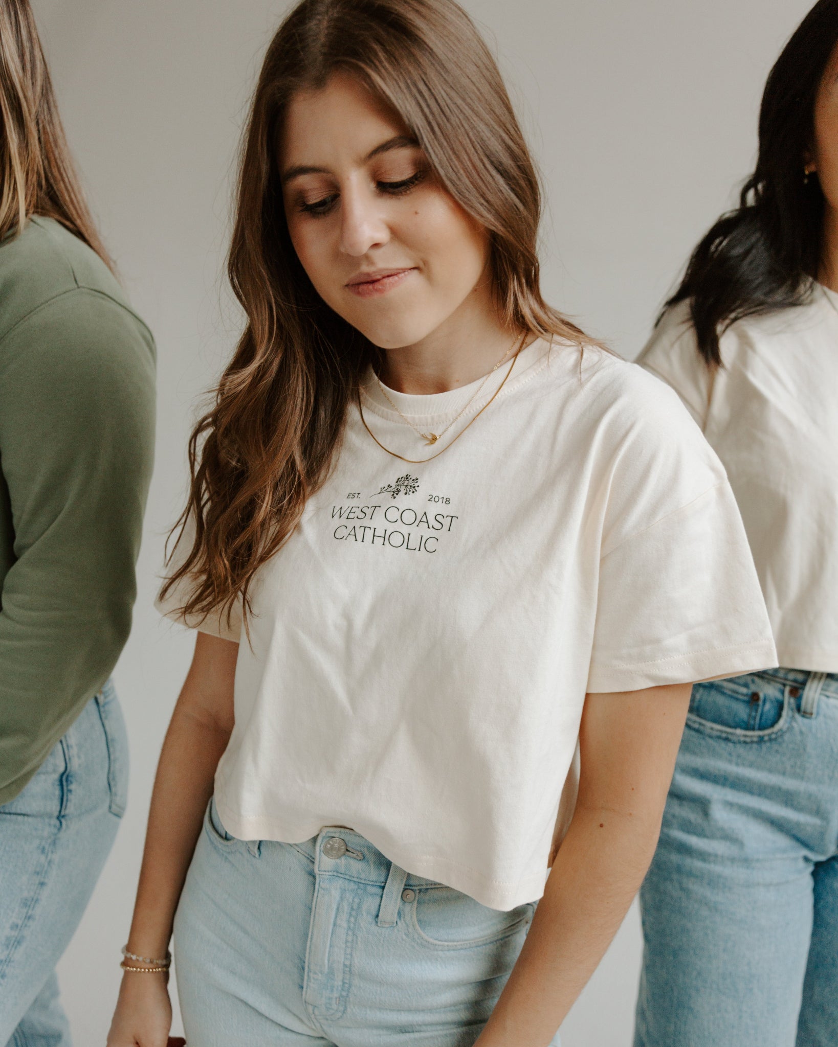 A person wearing a beige 'WCC Boxy Tee' with text on it, paired with light blue jeans.