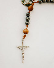 Rosary with gunmetal and wood beads and a silver cross on white background