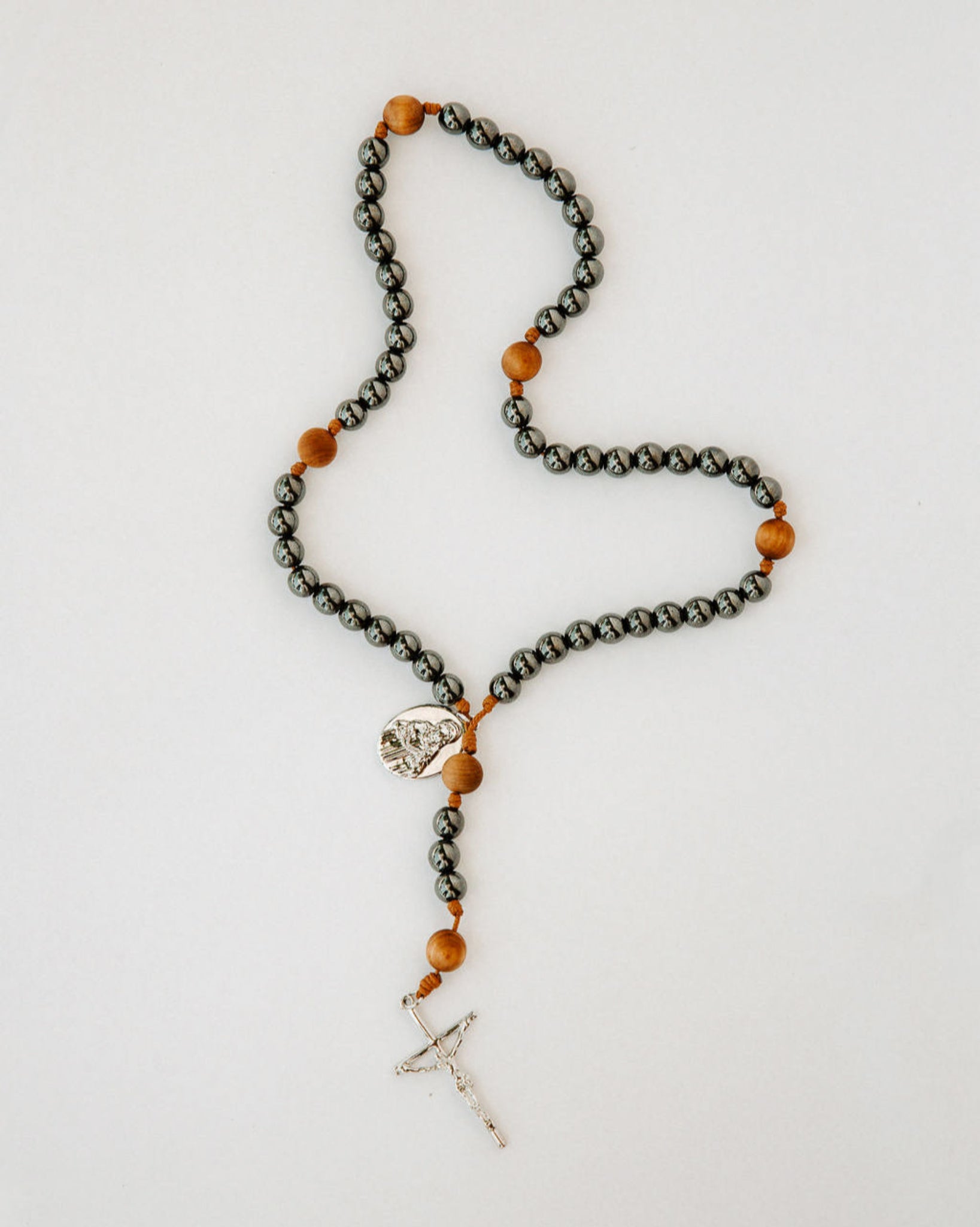 Rosary with metal and wood beads on white background