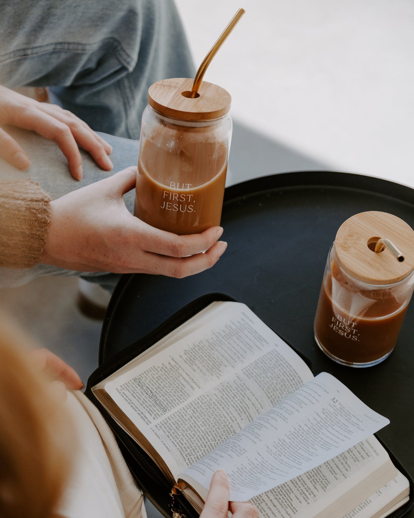 Hand holding jesus first tumbler and bible on black table