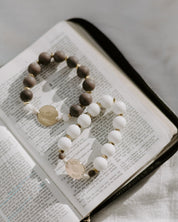 Rosary with wooden and white beads on an open book