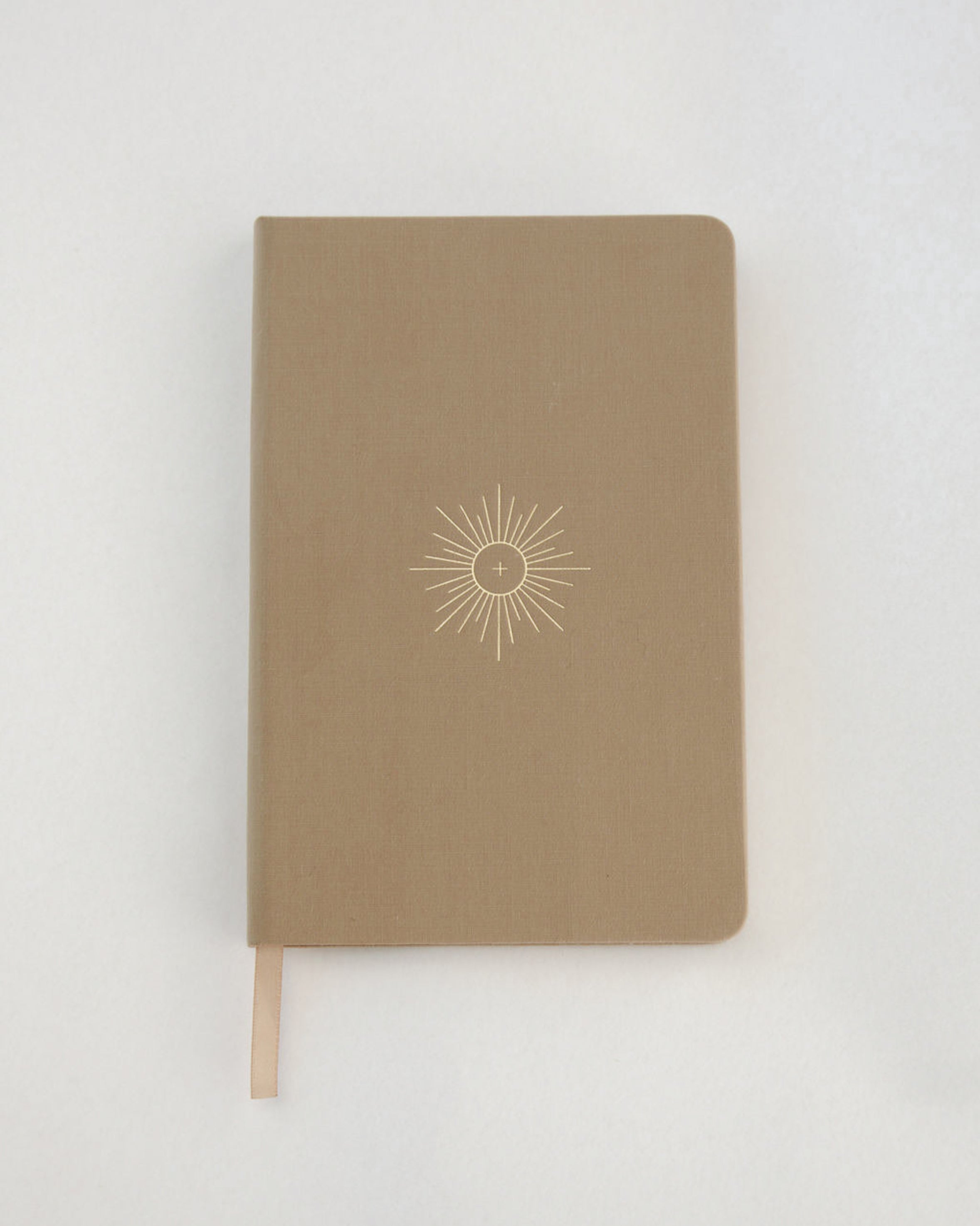 Brown notebook with linen cover and a eucharist emblem embossed on a white background