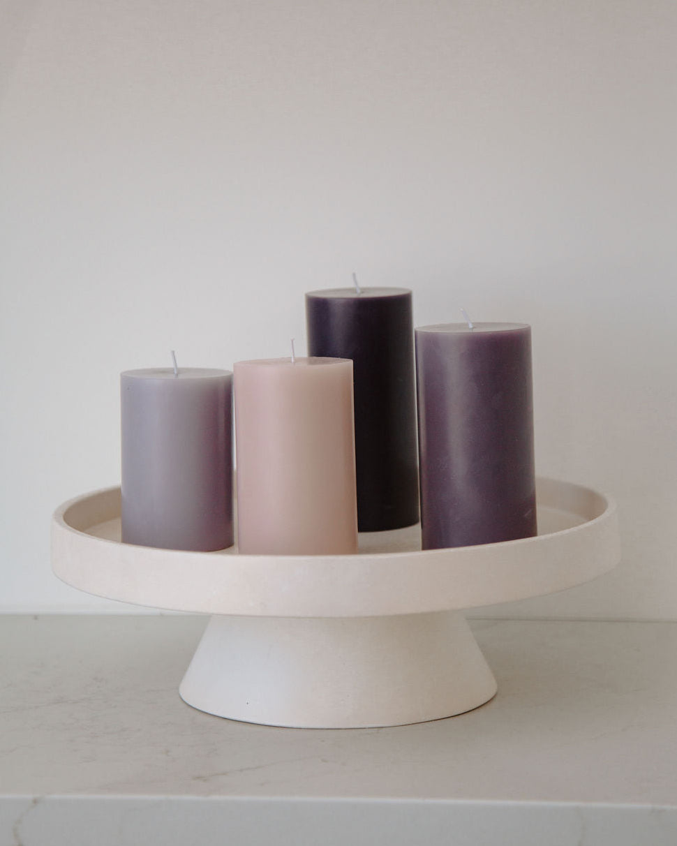 Set of purple candles on a white stand against a plain background