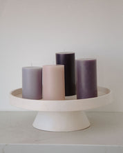 Set of purple candles on a white stand against a plain background