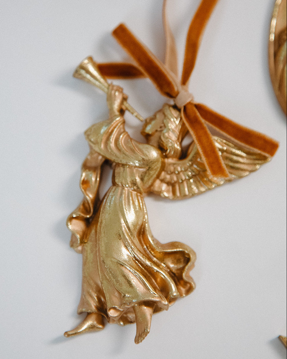 Gold angel ornament with a ribbon on a white background