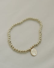 Gold Miraculous Medal beaded bracelet light gray background