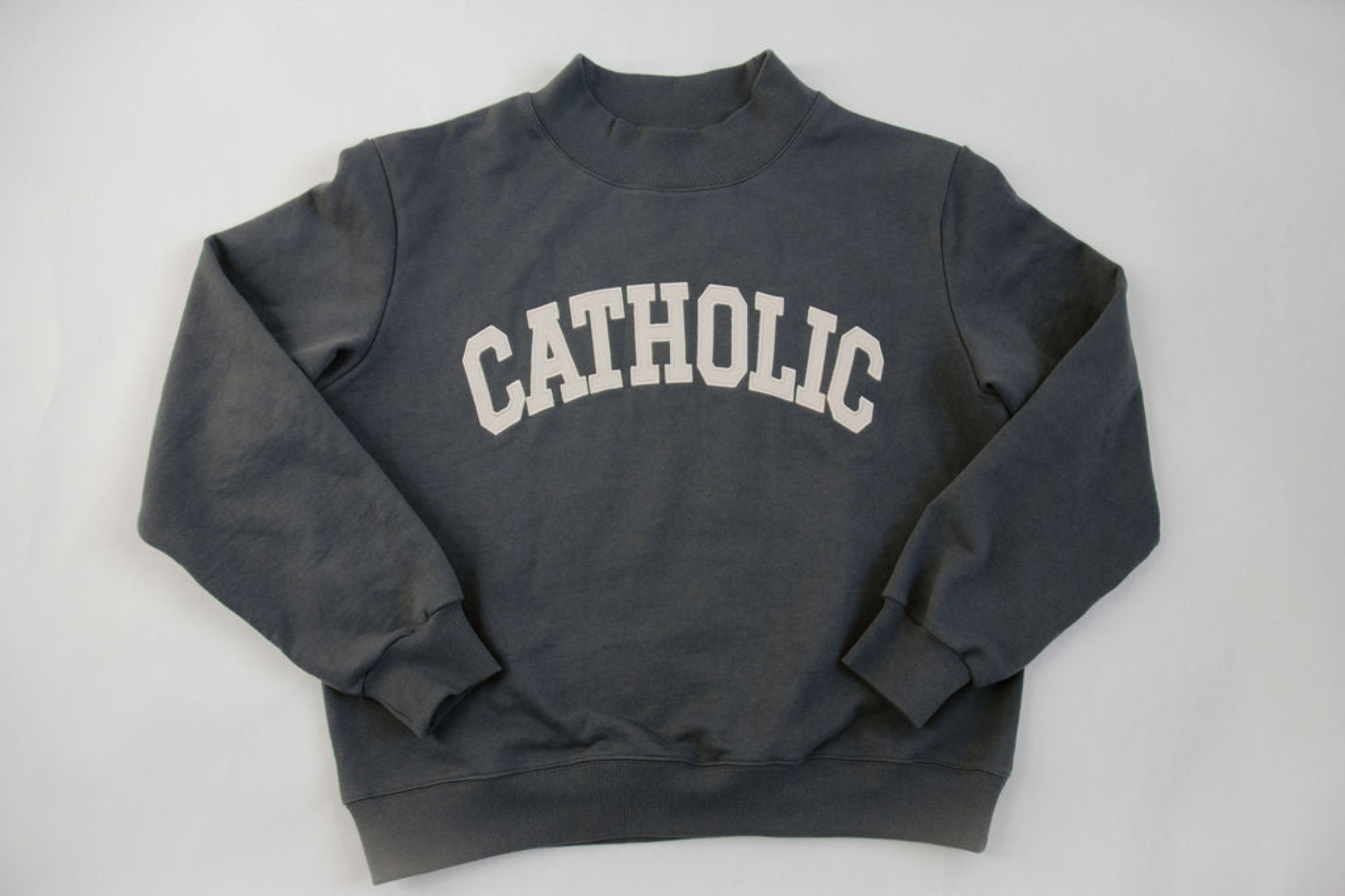 Gray sweatshirt with 'Catholic' text on a white background