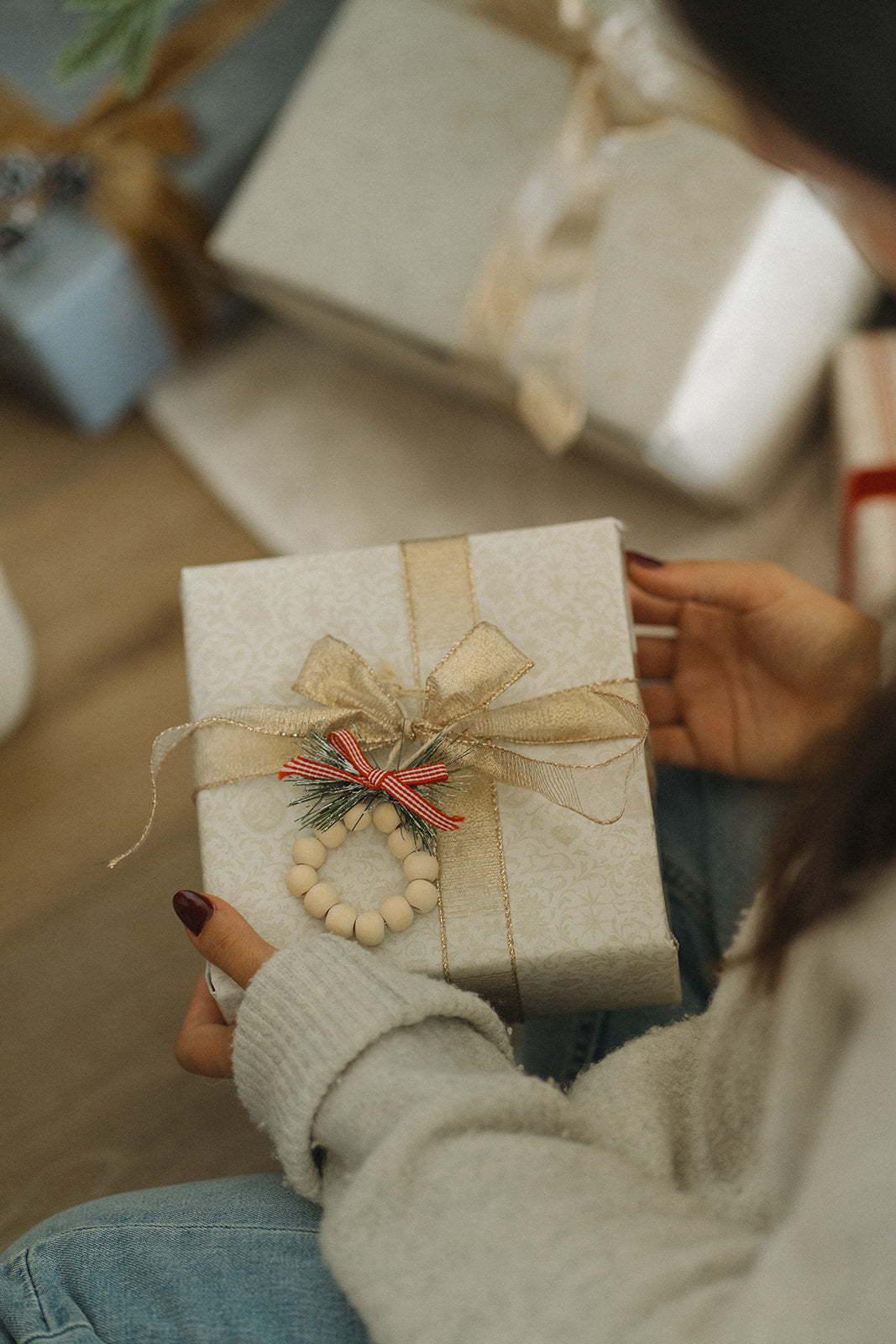 Person holding a gift box with a decorative bow in a festive setting