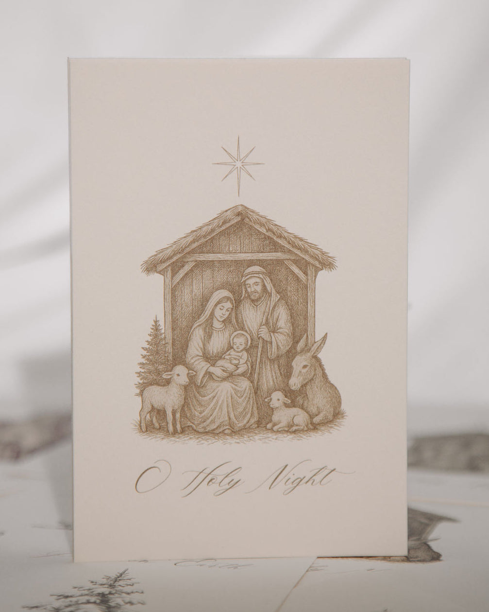 Nativity scene illustration on a card with 'O Holy Night' text, on a textured surface.