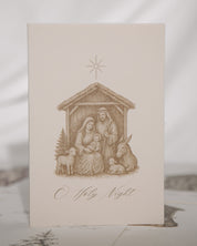 Nativity scene illustration on a card with 'O Holy Night' text, on a textured surface.