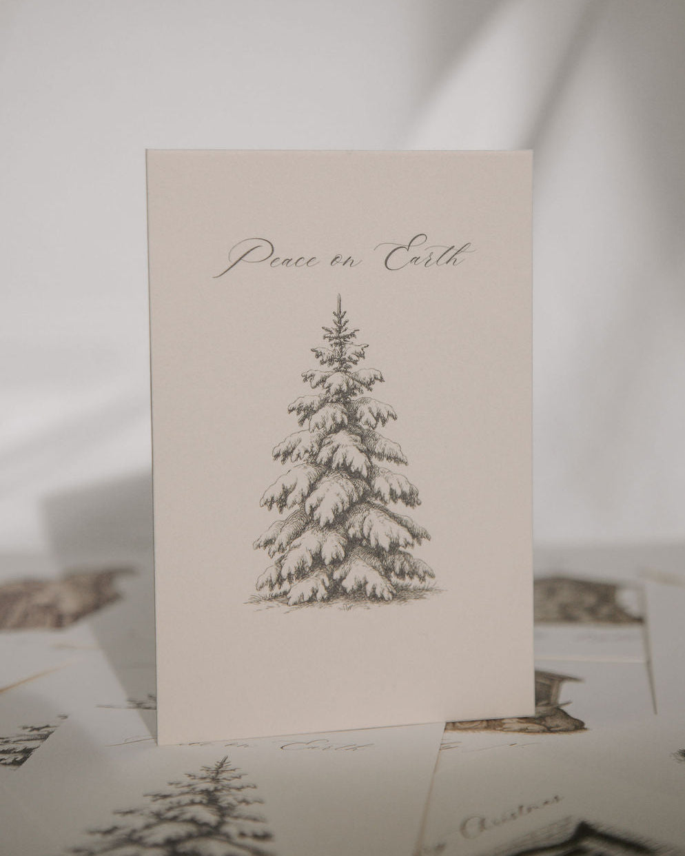 Card with a pine tree illustration and 'Peace on Earth' text on a light background
