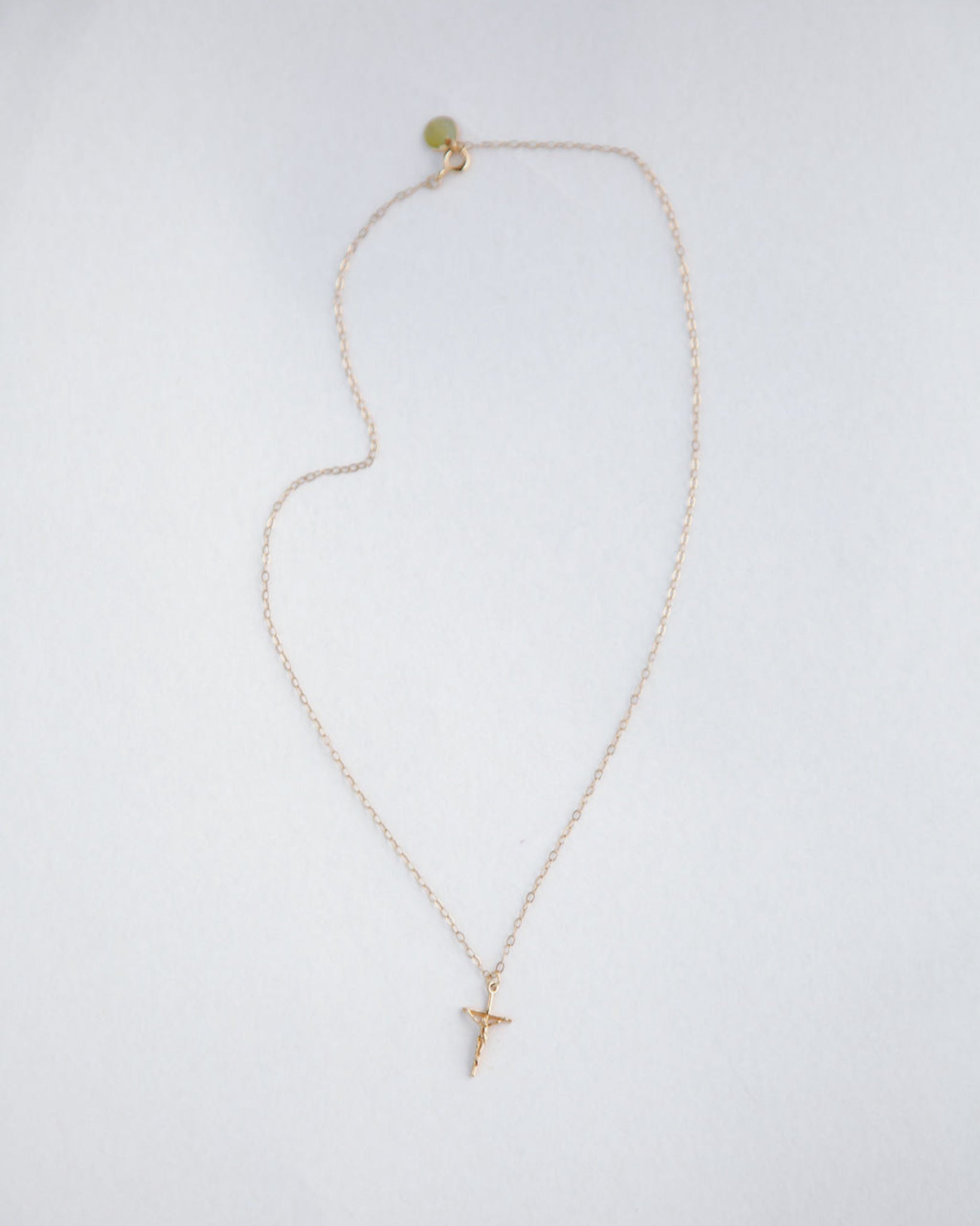 Gold necklace with a small cross pendant on a white background