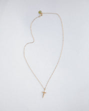 Gold necklace with a small cross pendant on a white background