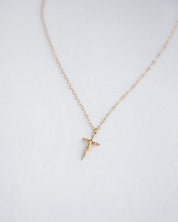 Dainty Crucifix Gold necklace on blurred white background