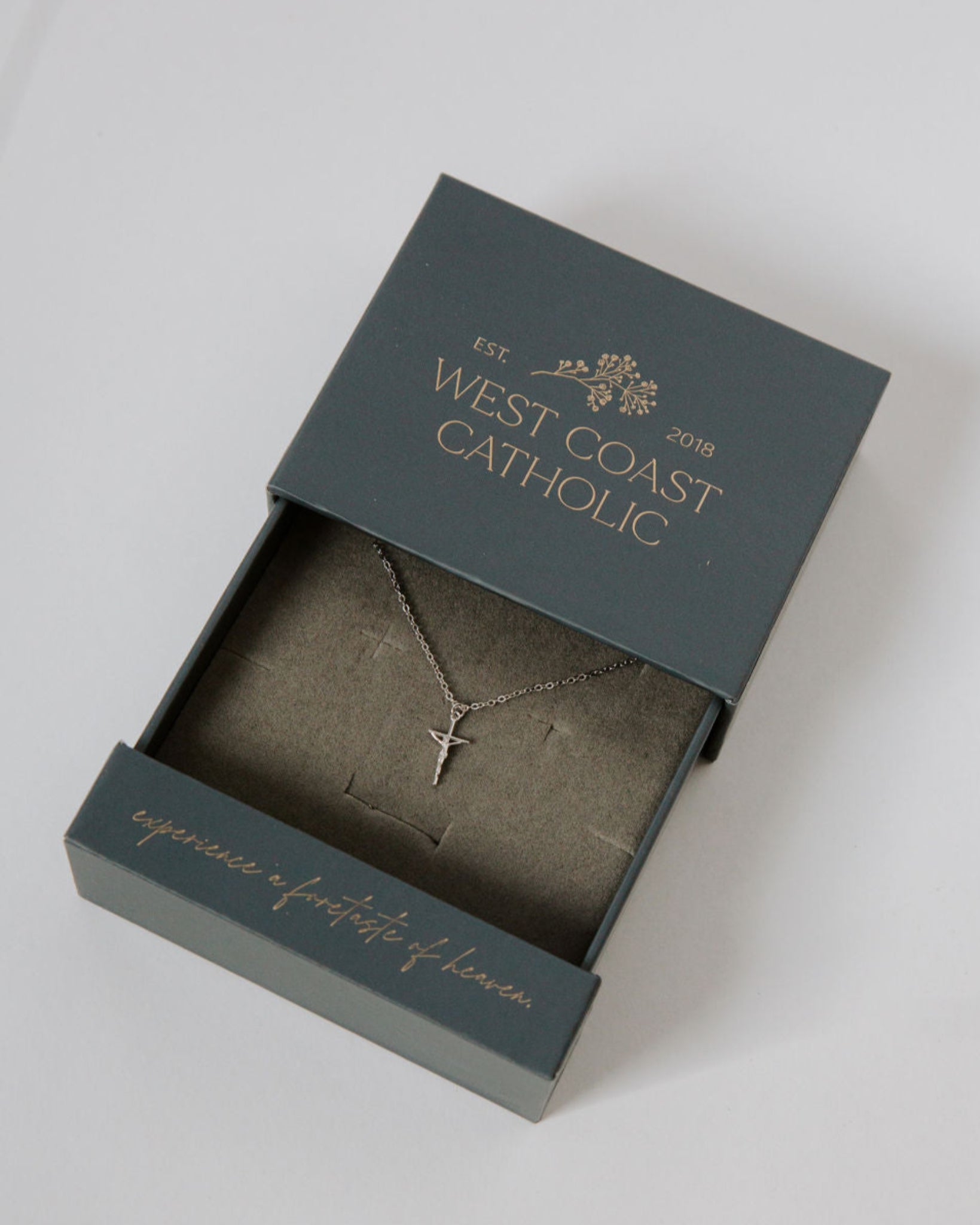 Dainty crucifix silver necklace in a gift box on a white background