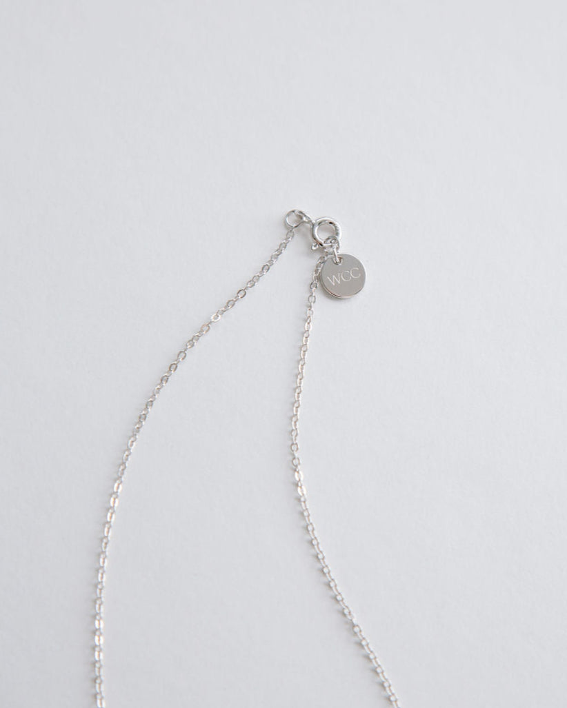 Silver cross necklace on a light gray background