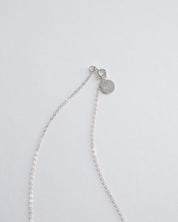 Silver cross necklace on a light gray background