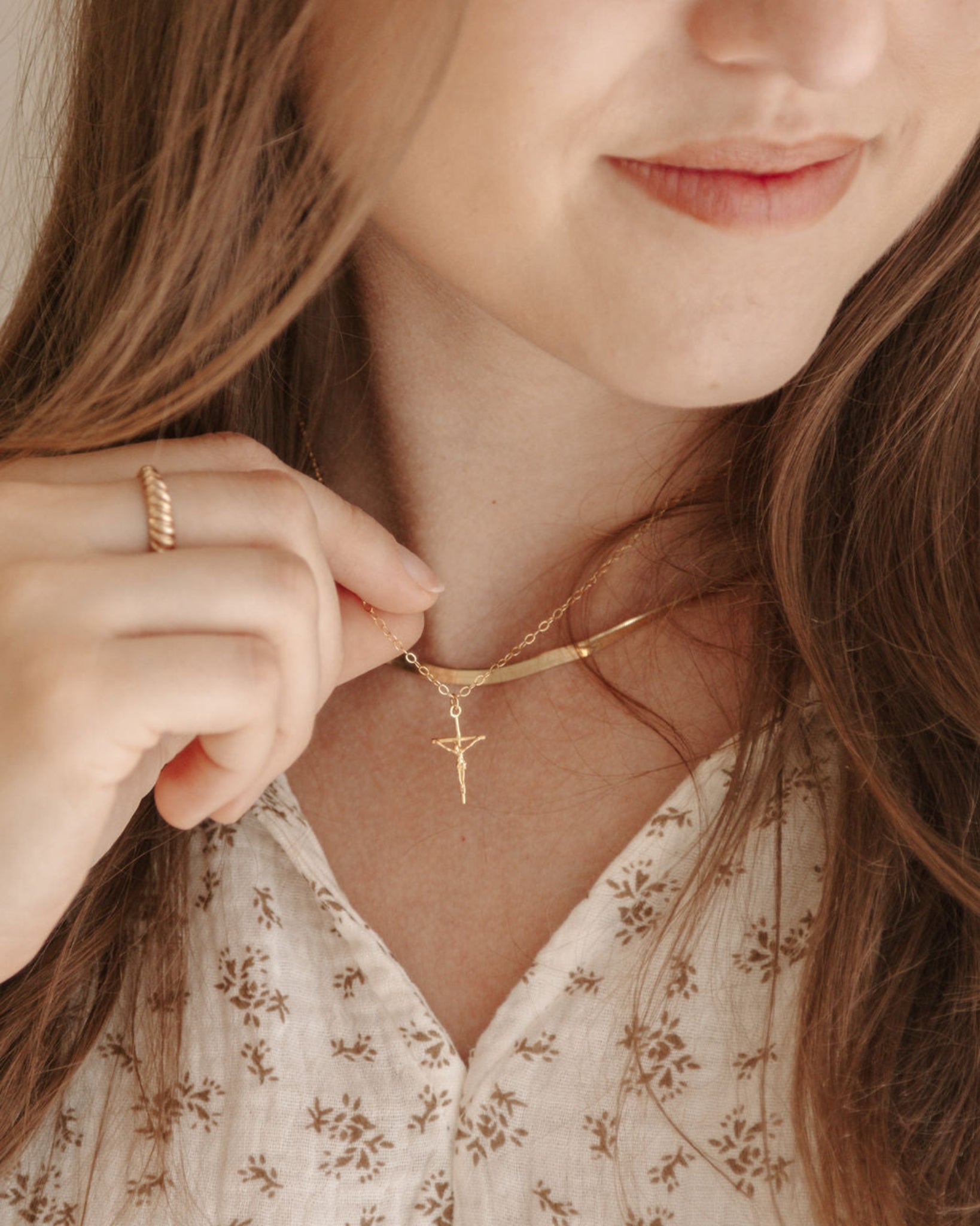 Close-up of a person wearing a gold necklace with a cross pendant.