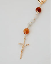 Rosary with white and orange beads and gold medal details on a white background