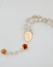 Rosary with white and orange beads and gold medal on a white background
