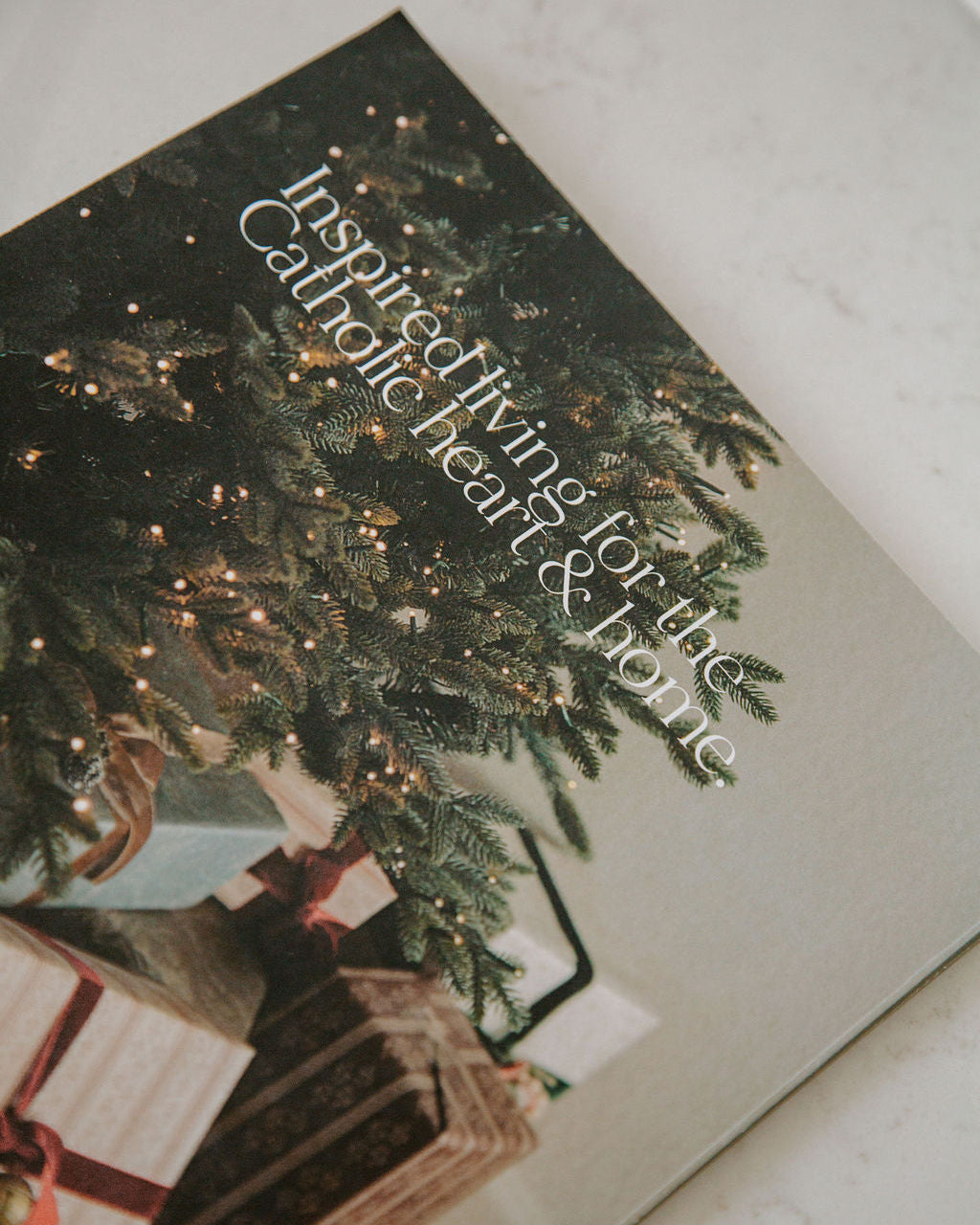 Magazine with Christmas tree and gift exchange scene, text 'Inspired living for the Catholic heart & home'.