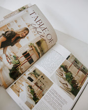 Open magazine with a focus on interior design, featuring images of a woman and a room.