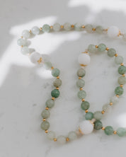 Lourdes rosary green and white beads with gold accents on white background
