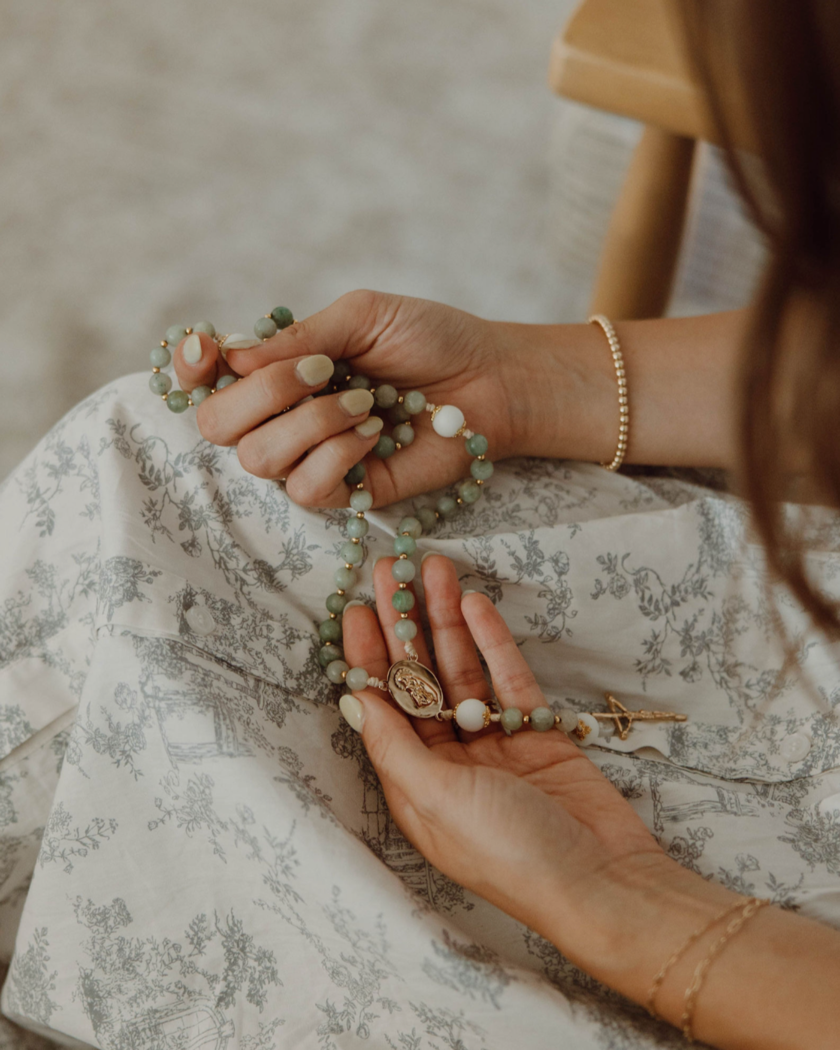 Woman holding lourdes rosary in prayer with blurred background