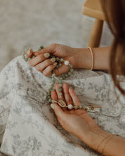Woman holding lourdes rosary in prayer with blurred background