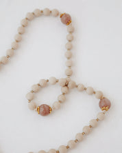 Rosary with beige and pink beads and a gold details on a light background