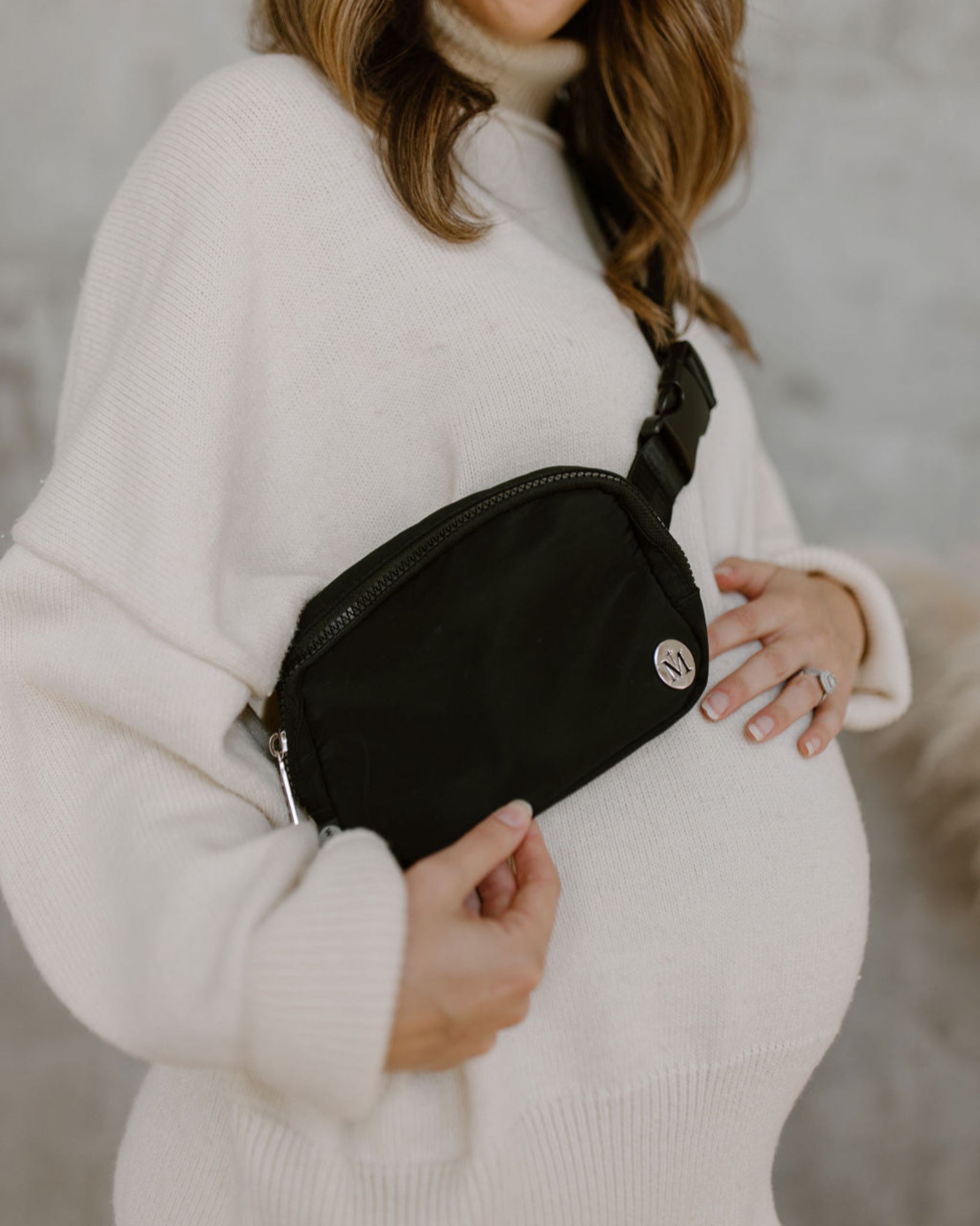 Woman wearing a black waist bag with a neutral background