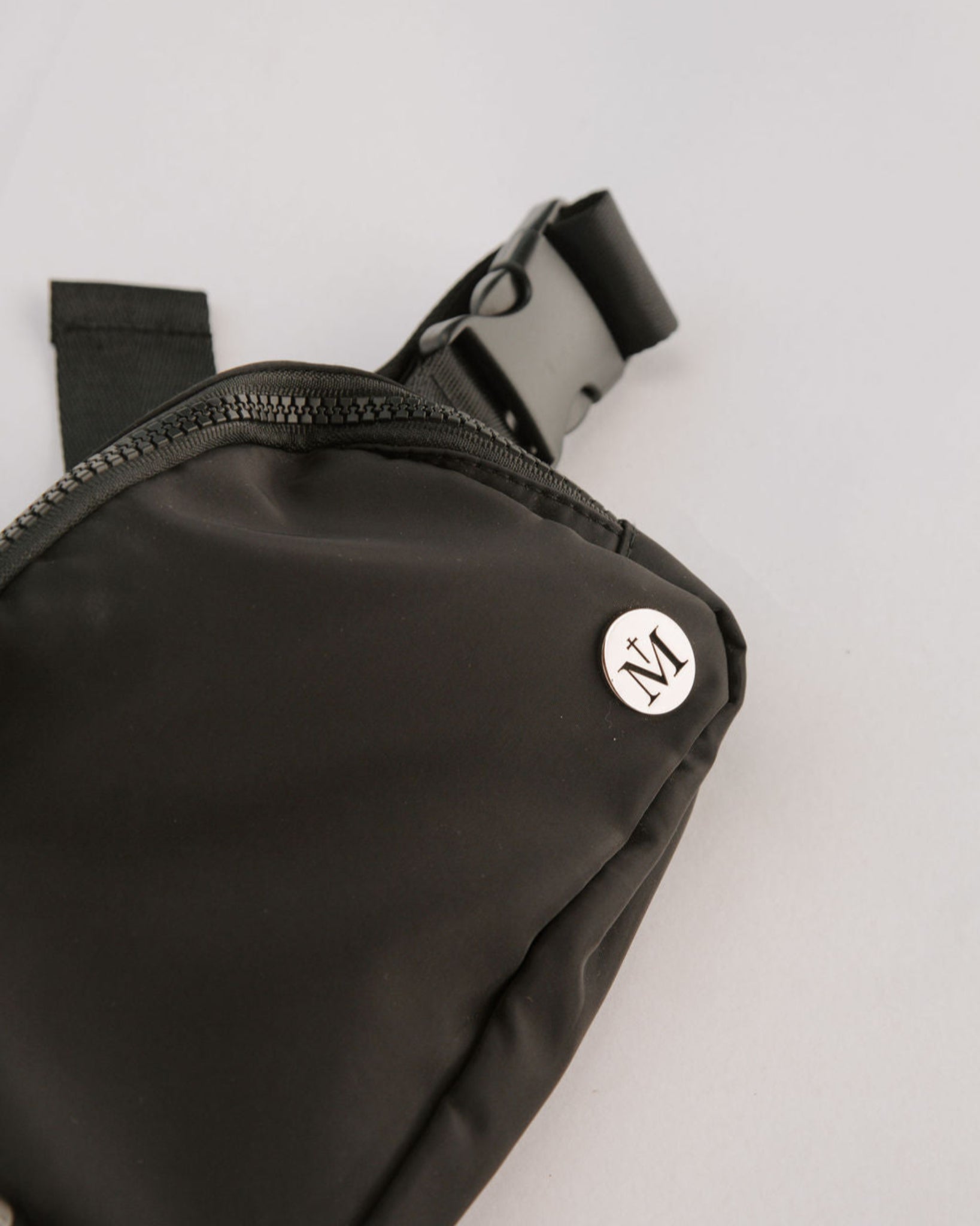 Black belt bag with a brand logo on a light gray background