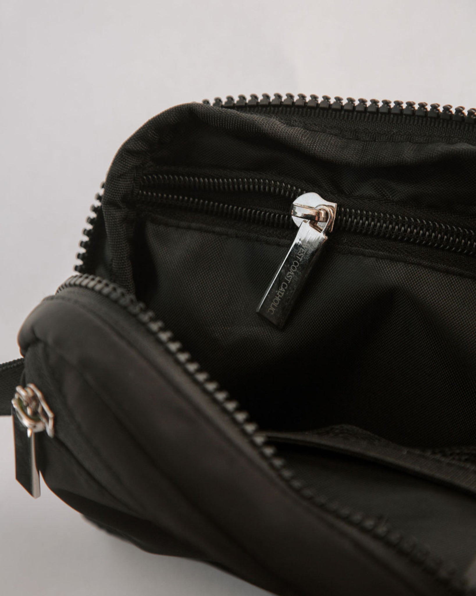 Close-up of a black bag with zippers on a light gray background