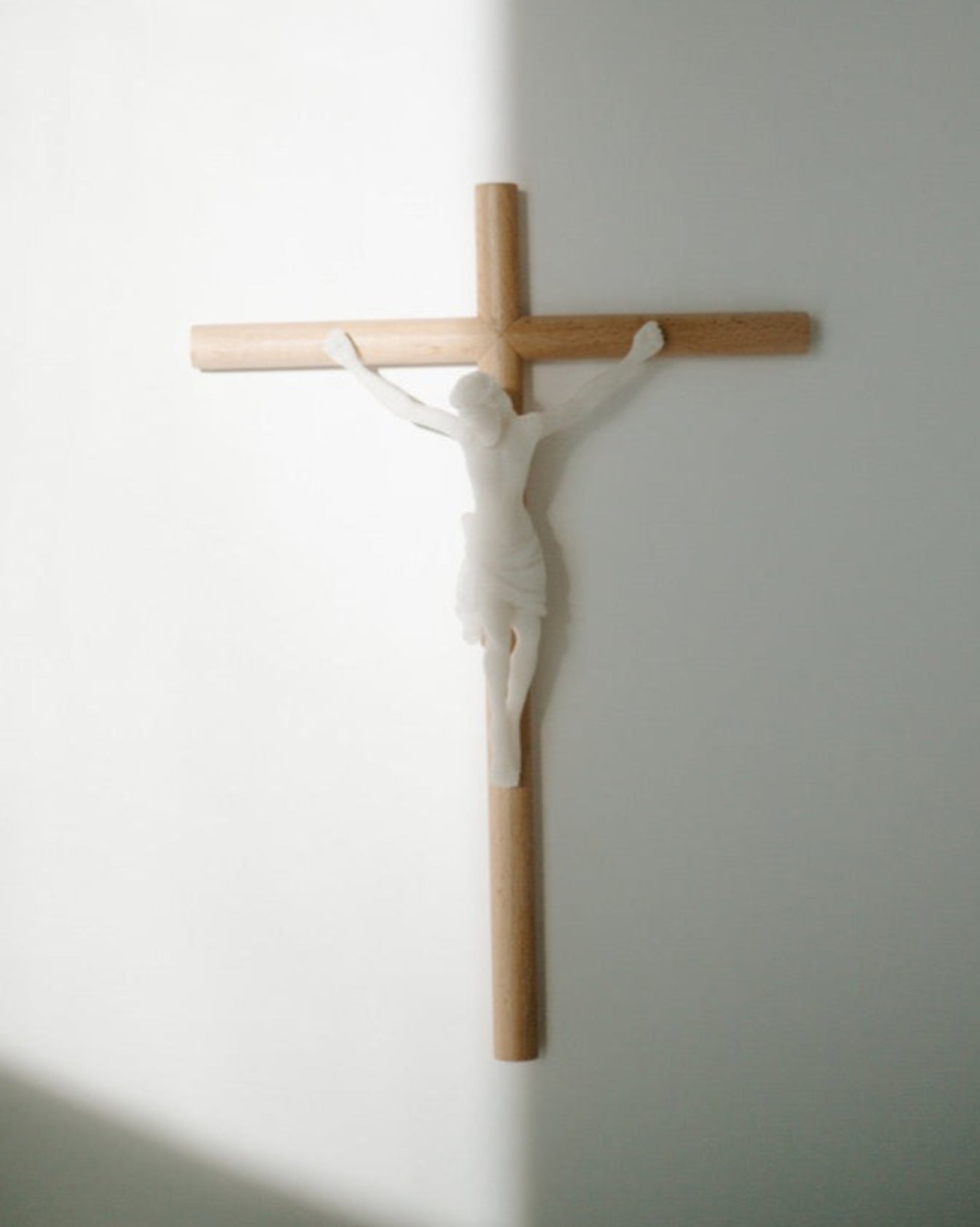 Modern wall crucifix hung on white wall with shadows