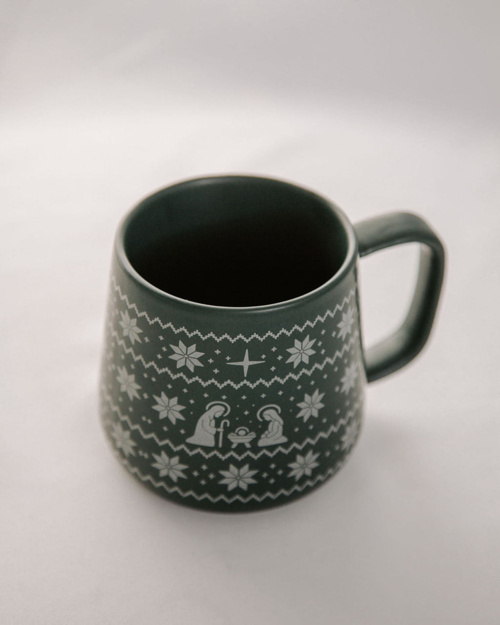 Green mug with white pattern on a light gray background
