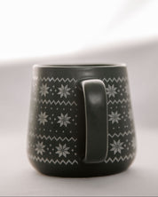 Green mug with white snowflake pattern on a light gray background
