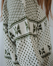 Close-up of a patterned sweater with green and black designs on a white background