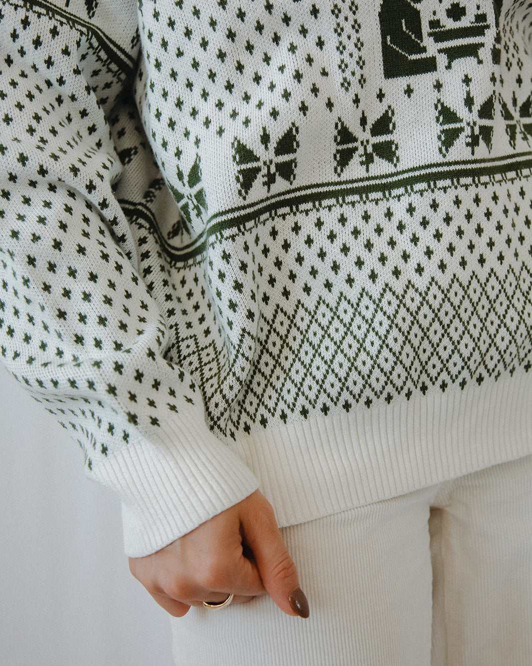 Close-up of a person wearing a white sweater with black pattern
