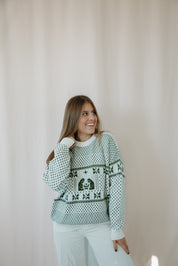 Woman wearing a green patterned sweater against a plain background