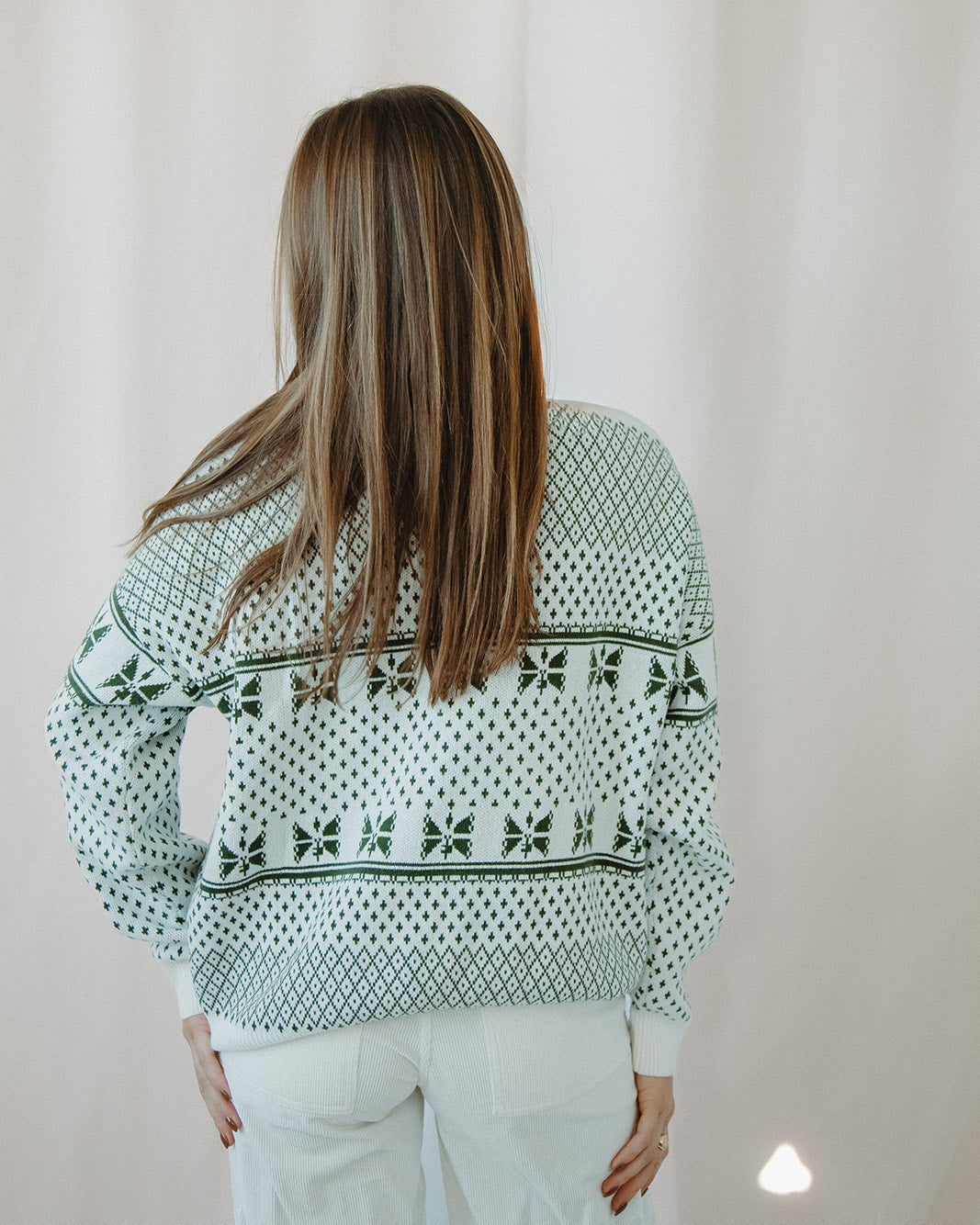 Person wearing a patterned sweater with a plain background