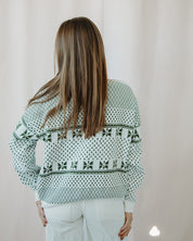 Person wearing a patterned sweater with a plain background