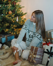 Woman sitting by a decorated Christmas tree with presents around her.