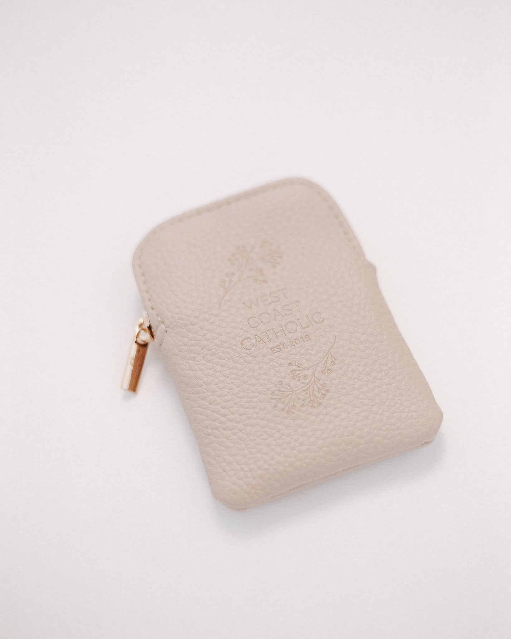 Beige leather rosary pouch with embossed logo on a white background