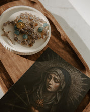 Rosary on a white dish with a religious-themed our lady of sorrows card underneath