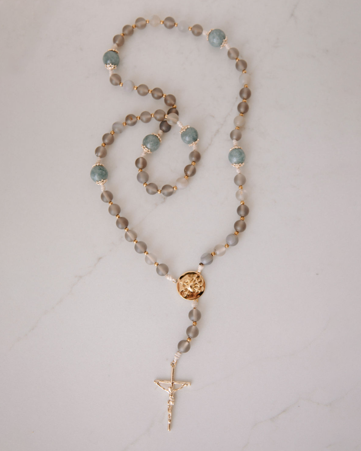 Rosary with brown and blue beads with gold medal and crucifix on a white background