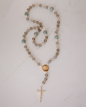 Rosary with brown and blue beads with gold medal and crucifix on a white background