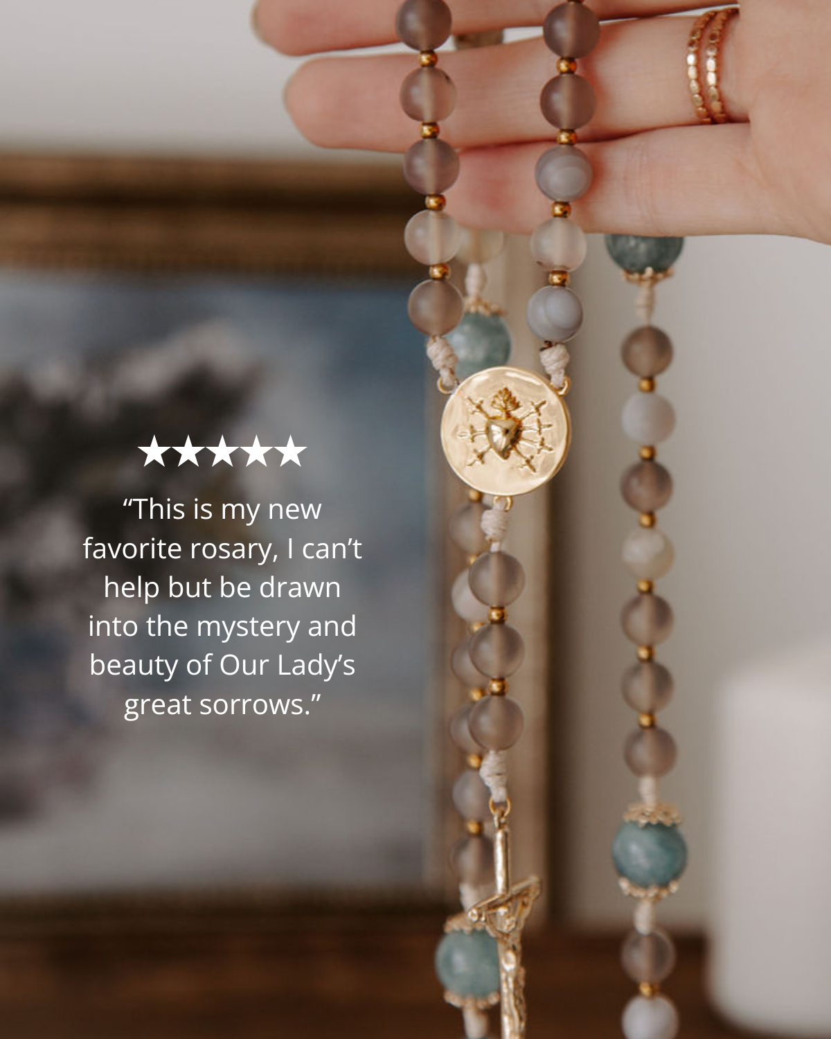 Close-up of a rosary with a gold medal, held by a hand, with a blurred background with 5 star review