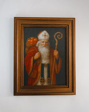 Framed painting of a robed figure with a staff and pumpkin on a white wall