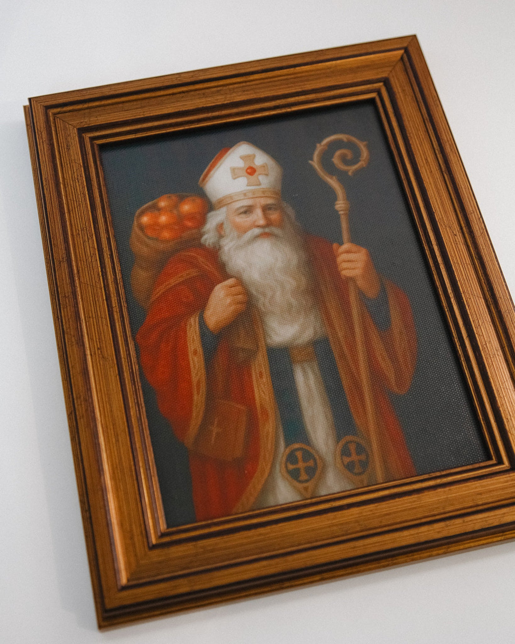 Framed painting of a robed figure with a staff on a white wall
