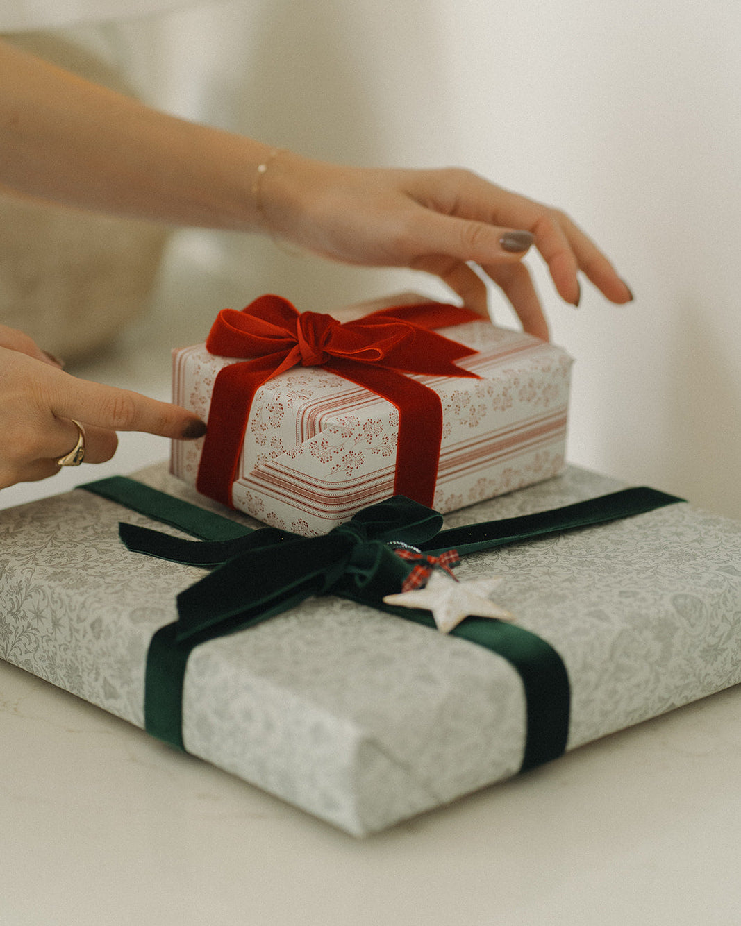 Two wrapped gifts with red and green ribbons on a light surface.